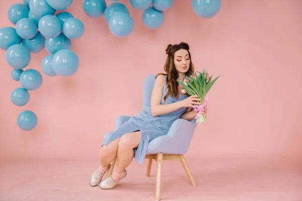 Menina em um vestido azul em um quarto rosa com uma poltrona azul e blu — Fotografia de Stock