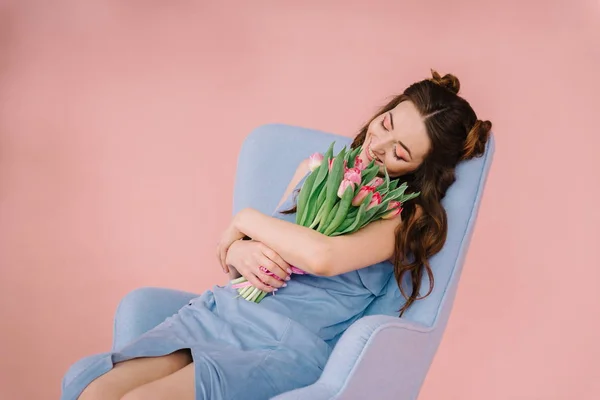 Menina em um vestido azul em um quarto rosa com uma poltrona azul e um b — Fotografia de Stock