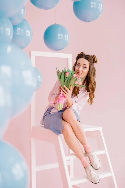 Menina em um vestido azul em um quarto rosa com um buquê de tulipas em — Fotografia de Stock