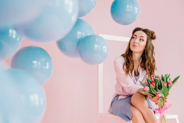 Menina em um vestido azul em um quarto rosa com um buquê de tulipas em — Fotografia de Stock