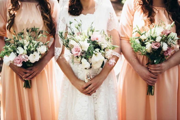 Dvě kamarádky a nevěsta drží krásné svatební kytice v t — Stock fotografie