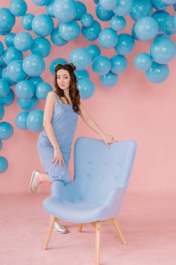 bir mavi sandalye ve mavi b ile pembe bir odada mavi elbiseli kız