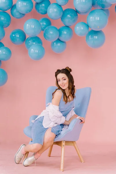 Menina bonita em um vestido azul em uma sala rosa com bolas azuis e — Fotografia de Stock