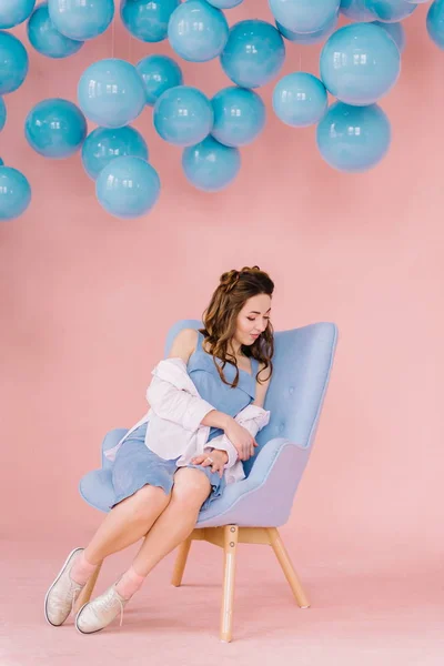 Menina bonita em um vestido azul em uma sala rosa com bolas azuis e — Fotografia de Stock