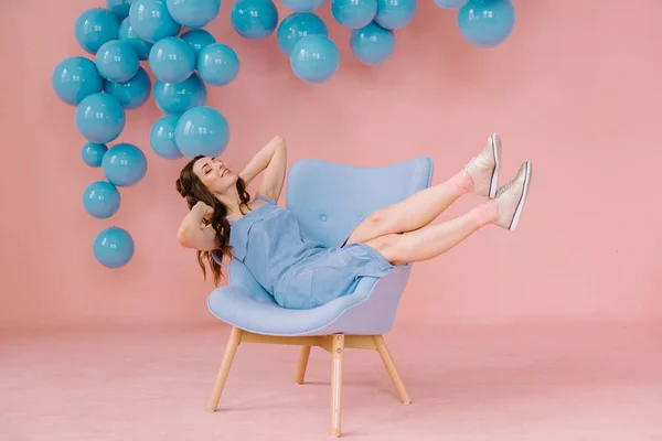 Menina em um vestido azul em um quarto rosa com uma cadeira azul e b azul — Fotografia de Stock