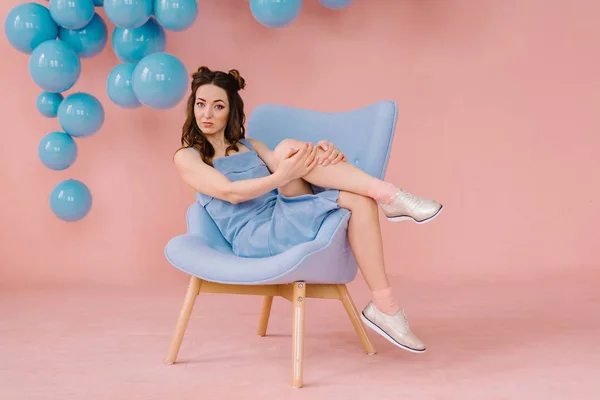 Menina em um vestido azul em um quarto rosa com uma cadeira azul e b azul — Fotografia de Stock