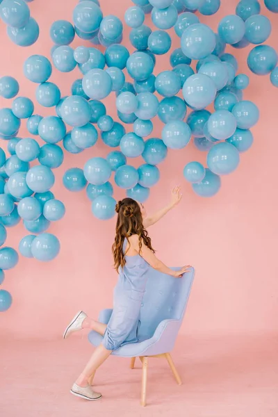 Uma menina de pequena estatura em uma sala rosa está jogando com bola azul — Fotografia de Stock