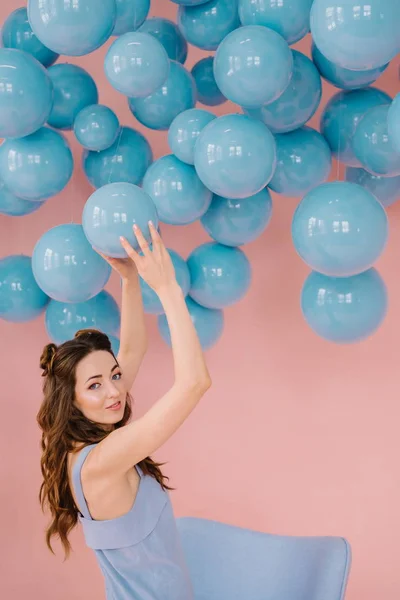 Dziewczyna z niskiego wzrostu w różowym pokoju bawi się z niebieską piłkę — Zdjęcie stockowe