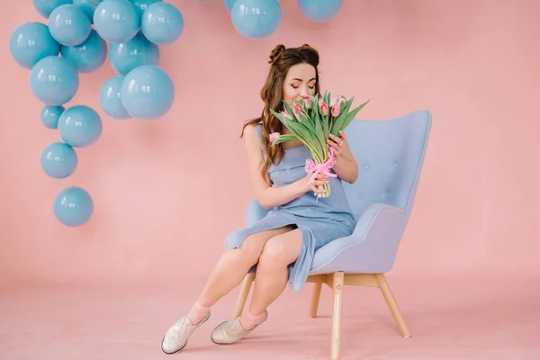 Menina em um vestido azul em um quarto rosa com uma poltrona azul e blu — Fotografia de Stock