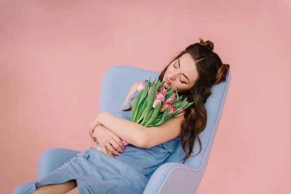 Menina em um vestido azul em um quarto rosa com uma poltrona azul e um b — Fotografia de Stock