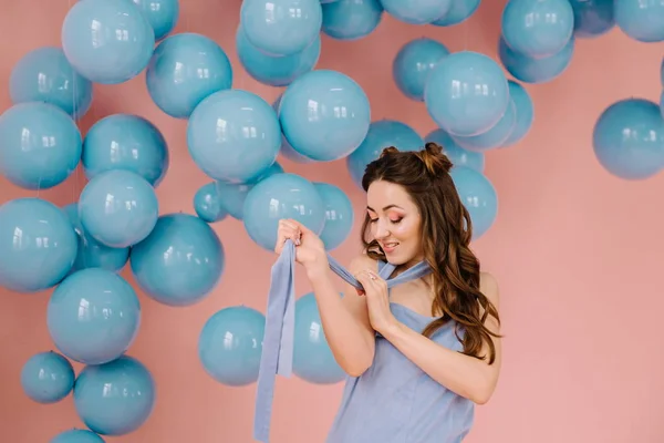 Uma menina macia em um vestido azul, em uma sala rosa jogando uma costela azul — Fotografia de Stock