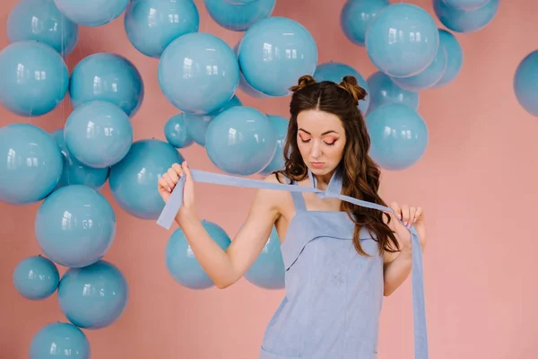 Uma menina macia em um vestido azul, em uma sala rosa jogando uma costela azul — Fotografia de Stock