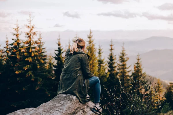 A menina senta-se em uma rocha e fotografias montanhas — Fotografia de Stock