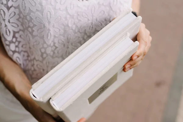 two albums for wedding photography in a white velvet cover with thick pages with shallow depth of field in the hands of a girl