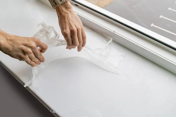 A worker removes plastic film from the window sill