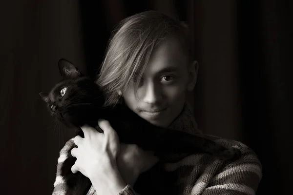 Joven con un gato negro posando delante de la cámara —  Fotos de Stock