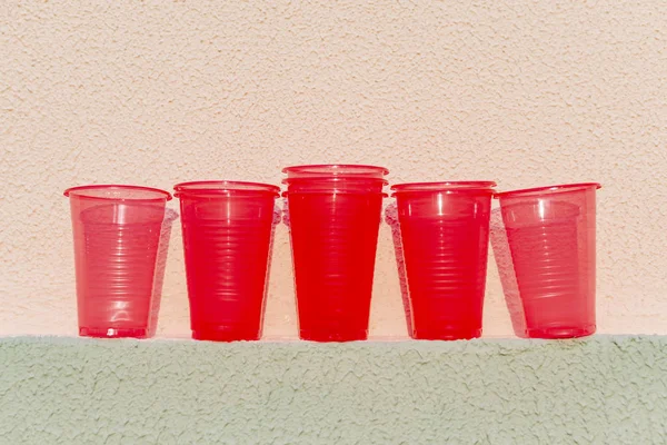 Red plastic cups are on the wall of the house