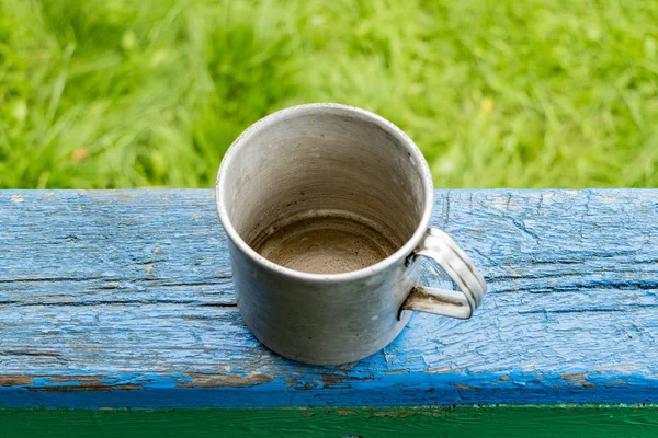 The old metal mug on the edge of the table is blue