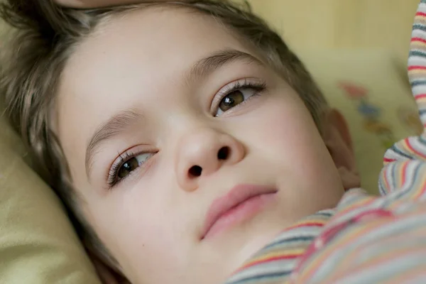 Un niño está acostado en el sofá de la casa. —  Fotos de Stock