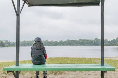 Küçük bir çocuk sonbaharda nehir kıyısında tek başına yürüyor.