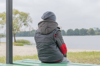 Küçük bir çocuk sonbaharda nehir kıyısında tek başına yürüyor.