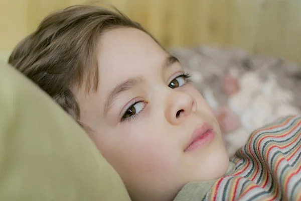 Ein kleiner Junge liegt auf der Couch im Haus — Stockfoto