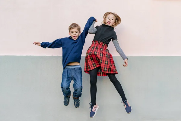 Jong meisje met jongere broer spelen, springen — Stockfoto