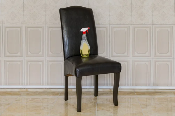 Fragment of a dark Executive chair and a bottle of detergent
