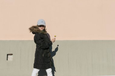 Siyah ceketli, yuvarlak şekerli genç bir kız kameranın önünde poz veriyor.