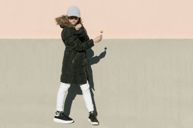 Siyah ceketli, yuvarlak şekerli genç bir kız kameranın önünde poz veriyor.