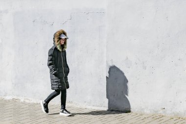 Siyah ceketli genç bir kız sokakta yürüyor.