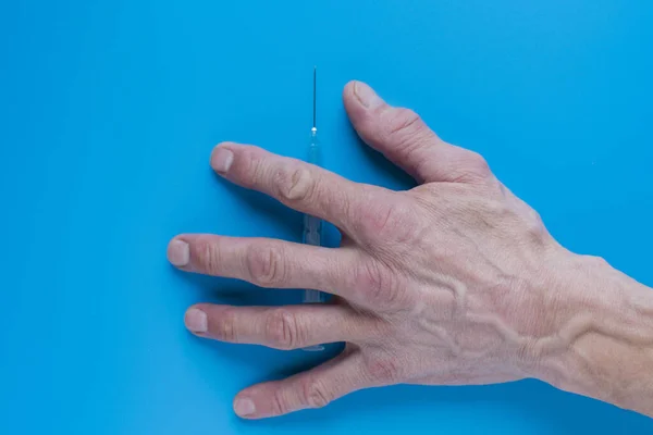 青い背景に大きな静脈を持つ注射器と大人の手 — ストック写真