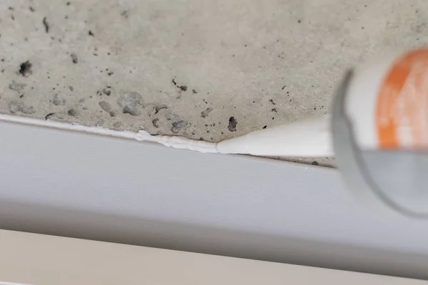 Kurucu silikonla çalışıyor, balkondaki alüminyum yapıyı kapatıyor.