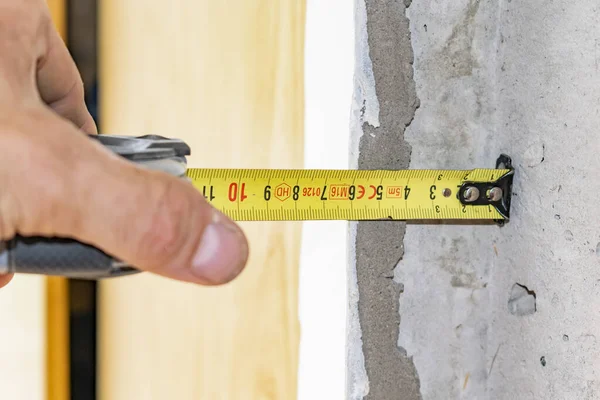 Bir işçi pencerenin açılışını mezura ile ölçer