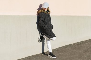 Siyah ceketli genç bir kız kameranın önünde poz veriyor.