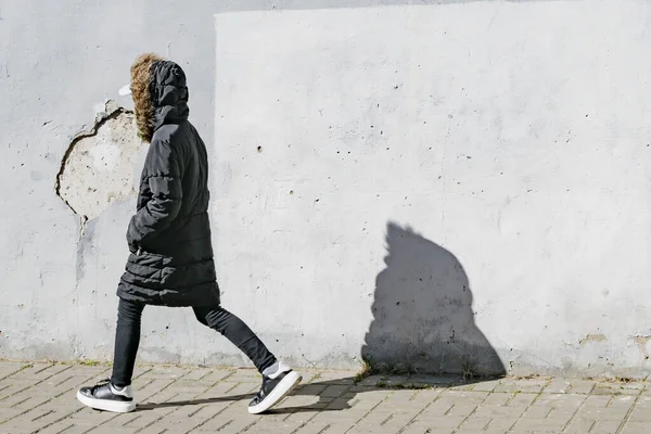 一个穿着深色夹克的小女孩在街上走着 — 图库照片