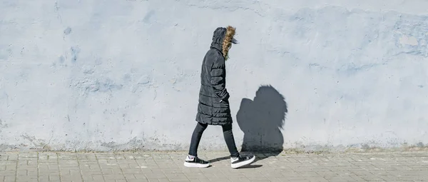 一个穿着深色夹克的小女孩在街上走着 — 图库照片