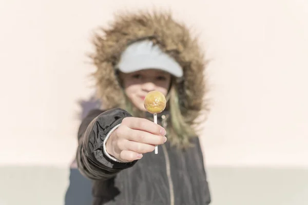 一个身穿深色夹克 头戴圆圆的糖果的小女孩站在摄像机前摆姿势 — 图库照片