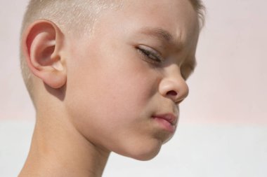 Kameraya poz veren beyaz tişörtlü küçük bir çocuk.