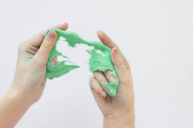 Çocukların elleri yeşil renkli yapışkan bir kütle ile oynar.