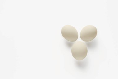 Hafif arka planda üç beyaz tavuk yumurtası.