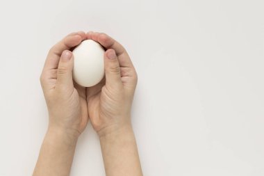 Çocuk elleri arka planda bir yumurta tutar.