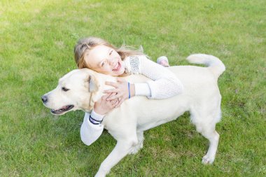 Küçük kız bahçede Labrador köpeğiyle oynuyor.