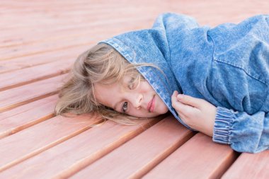 Bahçede oynayan kot ceketli küçük kız.