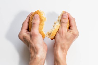 Bir adam bir somun taze beyaz ekmek kırıyor.