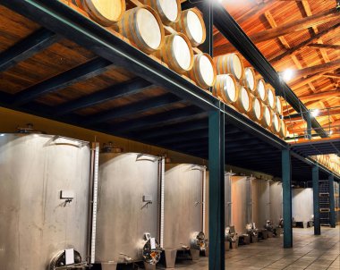Wine barrels and metal cisterns in dark cella clipart