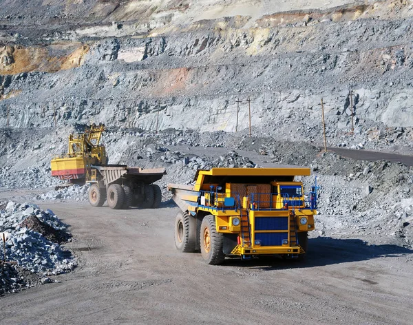 Excavator loading iron ore into heavy dump trucks on the opencas — Stock Photo, Image