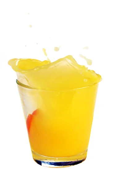 Splash w szklankę soku z spadające plasterek pomarańczy — Zdjęcie stockowe