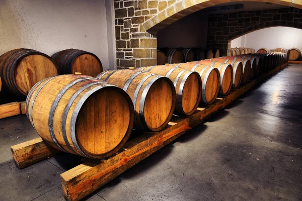 Barris de vinho e cisternas de metal em adega escura — Fotografia de Stock