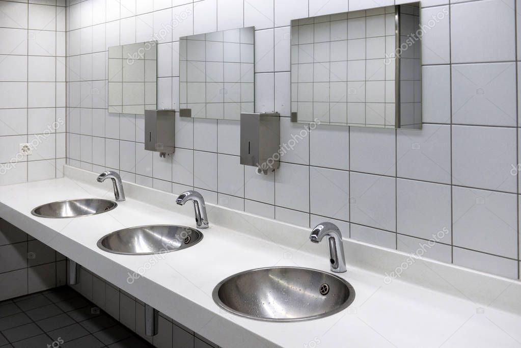 Blurred white washbasins and shiny faucets in toilet with flare 